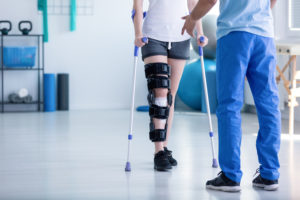 Professional physiotherapist supporting patient with orthopedic